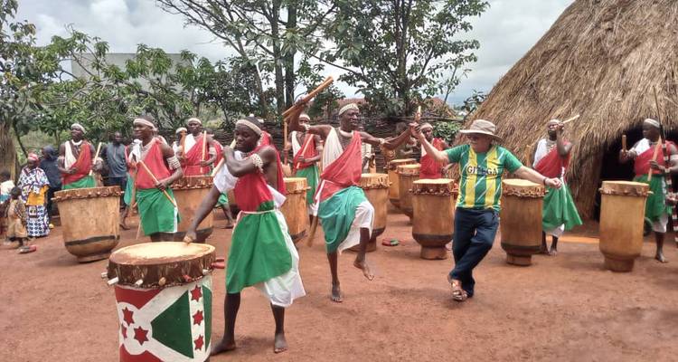 Energetic drum ensemble with tourists dancing among traditional musicians in an earthen courtyard.
