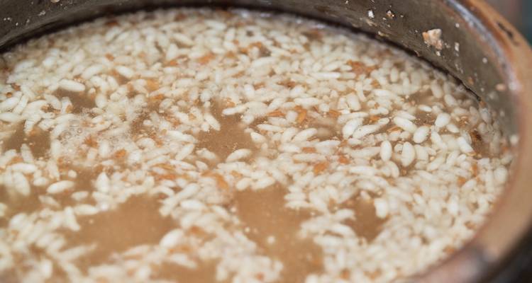 Nahaufnahme von gärenden Reiskörnern, die in einem traditionellen Tontopf mit Makgeolli schweben.