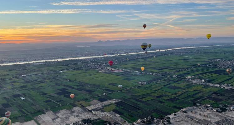 Large vue aérienne du Nil et des terres agricoles en patchwork parsemées de montgolfières au lever du soleil au-dessus de Louxor.