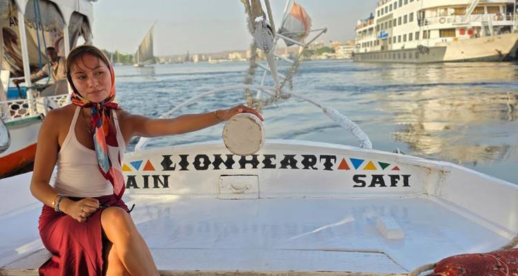 Mujer relajándose en un feluca en el Nilo con otros cruceros de fondo