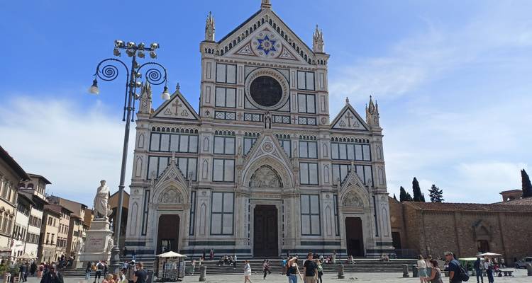 Facade of Basilica di Santa Croce in Florence with tourists scattered across the piazza.