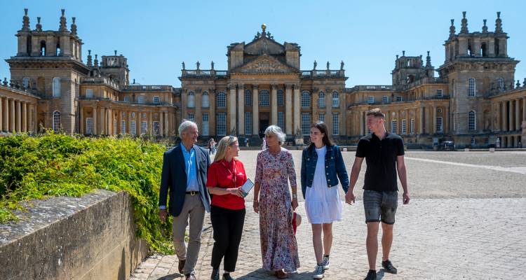 Guided group strolling the grand courtyard of Blenheim Palace on a bright day.