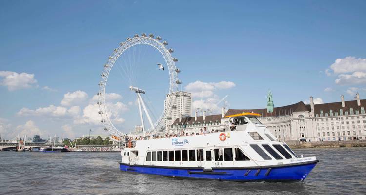 River cruise boat passes the London Eye giant wheel on a bright summer day.