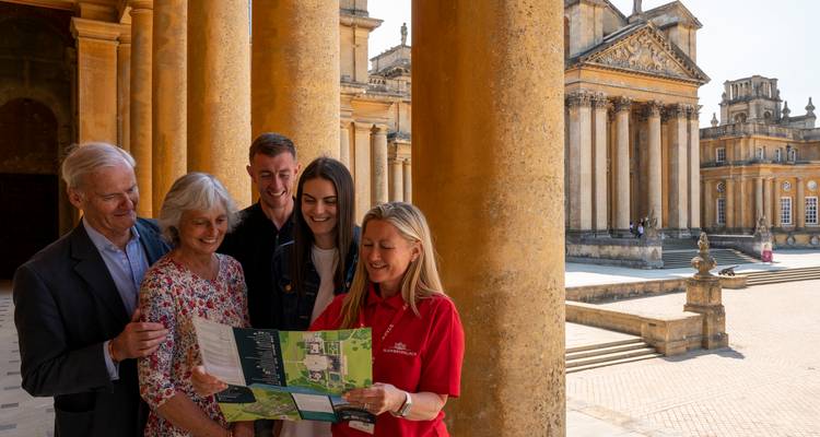 Visitors studying a map beneath the ornate stone columns of Blenheim Palace courtyard.