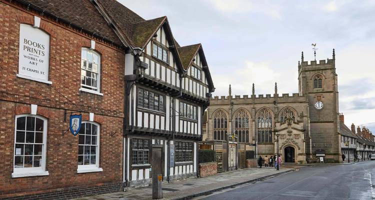 Timber-framed Tudor buildings and medieval church along quaint street in Stratford-upon-Avon.