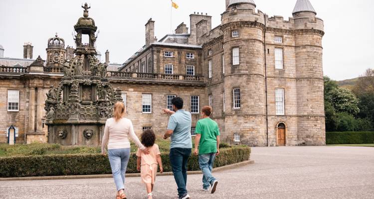 Family walking toward entrance fountain of the Palace of Holyroodhouse.