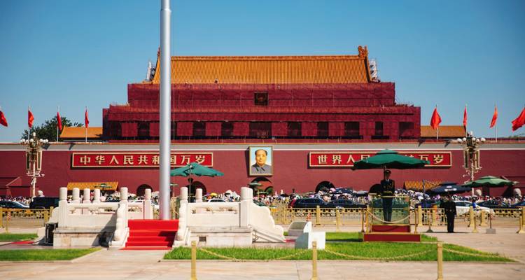The Tiananmen Gate with Mao portrait, red flags, and blue sky overhead.