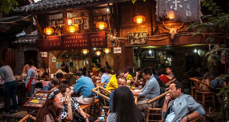 Bustling traditional teahouse in Chengdu filled with patrons sitting on bamboo chairs.