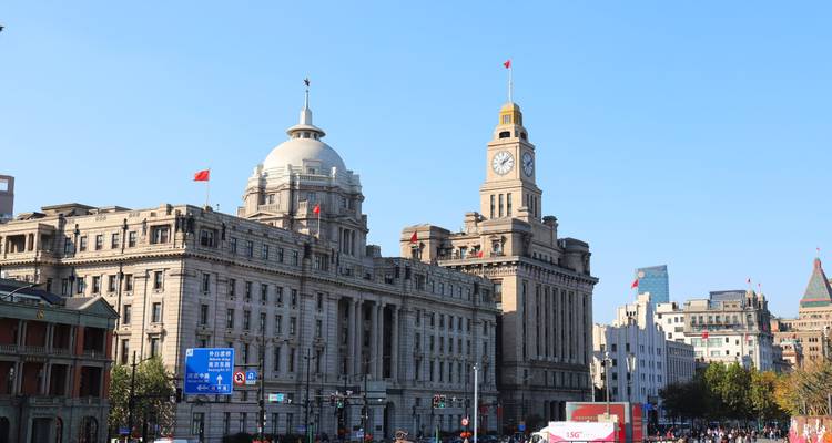 Historic European-style riverside buildings with clock tower and dome under a clear blue sky
