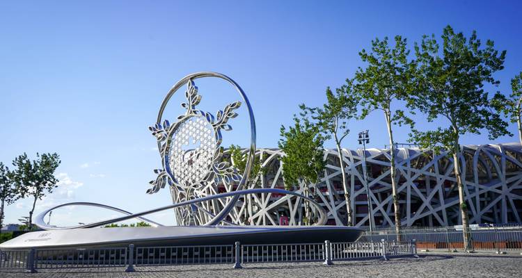 Beijing National Stadium (Bird’s Nest) with modern art sculpture and blue sky backdrop.