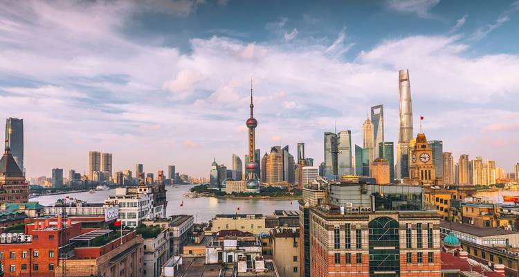 Skyline of Shanghai’s Pudong district with Oriental Pearl Tower and modern skyscrapers at dusk over the Huangpu River.