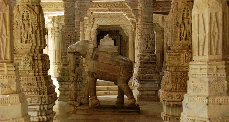 Pilares de mármol intrincadamente tallados y una estatua de elefante de piedra dentro del Templo Jainista de Ranakpur.
