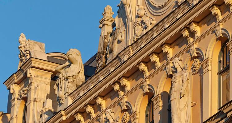 La lumière dorée frappant les sculptures ornées et les arcades de la façade d'un bâtiment de style Art nouveau.