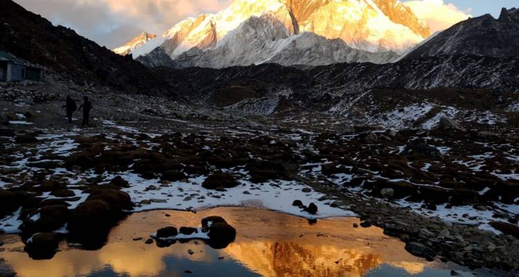Les pics enneigés de l'Himalaya se reflètent dans un bassin peu profond au lever du soleil doré près du camp de base de l'Everest.