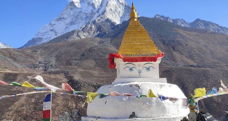 Stupa blanc orné de drapeaux à prières sous un pic enneigé spectaculaire dans la région du Khumbu.