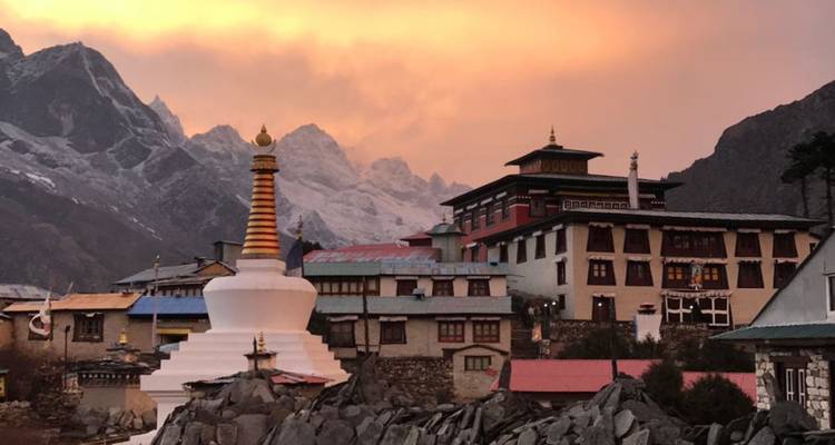 Le complexe du monastère de Tengboche en silhouette contre un coucher de soleil flamboyant avec les pics de l'Himalaya en arrière-plan.