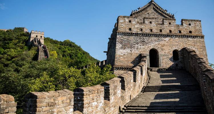 Stenen trappen die omhoog gaan naar een minder druk bezocht gedeelte van de Chinese Muur, omgeven door weelderig groen.