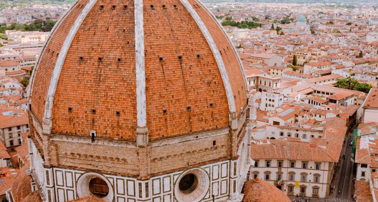 Primer plano de la cúpula de terracota del Duomo de Florencia elevándose sobre los tejados de la ciudad.