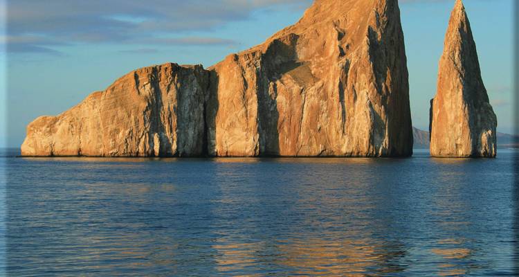 La formación de roca volcánica pura conocida como Kicker Rock se eleva dramáticamente desde el mar tranquilo durante la hora dorada.