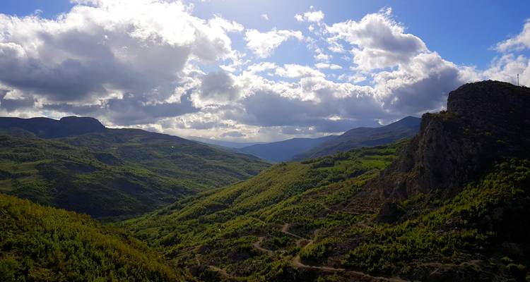 Un amplio valle de montaña verde bajo un cielo dramático en el sur de Albania.