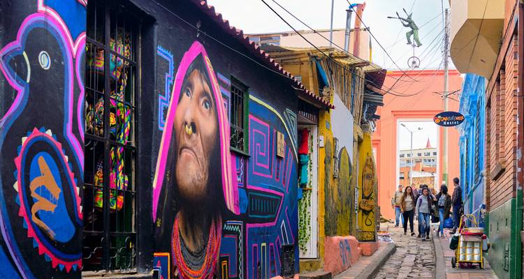 Callejón con arte callejero vibrante en La Candelaria de Bogotá que destaca un impresionante mural indígena.