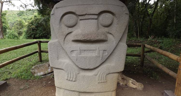 Una antigua estatua de piedra tallada se encuentra en los exuberantes alrededores verdes del parque arqueológico de San Agustín.