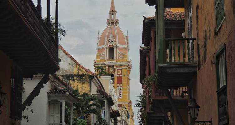 Vista a lo largo de una estrecha calle de Cartagena hacia la ornamentada cúpula de la catedral amarilla.