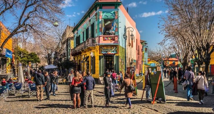 Levendige straatscène in La Boca met kleurrijke gebouwen, kunstkraampjes en drukke menigten in de zon.