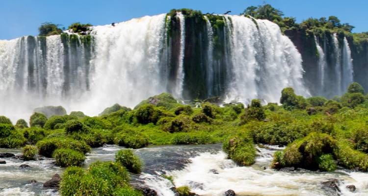 Krachtige waterval van de Iguazu Falls die naar beneden stort achter weelderige groene mosachtige rotsen.