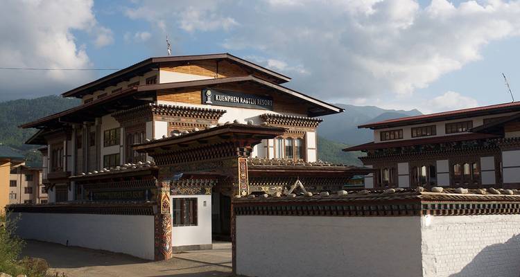 Complejo de museo de estilo bhutanés tradicional con madera tallada y paredes encaladas bajo un cielo azul.