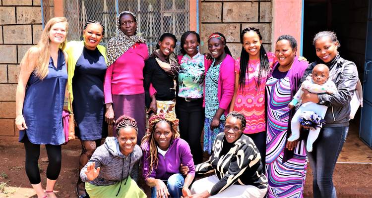Grupo grande de mujeres posando y sonriendo juntas fuera de un edificio de piedra.