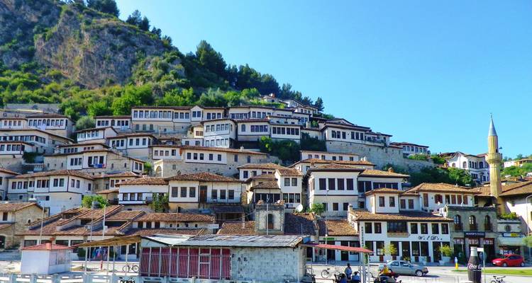 Une vue panoramique de la colline inscrite au patrimoine de l'UNESCO de Bérat, avec ses maisons en pierre densément construites sous un ciel bleu éclatant.