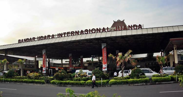 Fachada frontal del Aeropuerto Internacional Juanda con vehículos y viajeros.