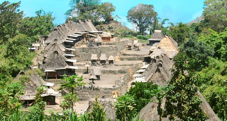 Vista aérea de un pueblo tradicional escalonado con filas de techos de paja en una ladera.