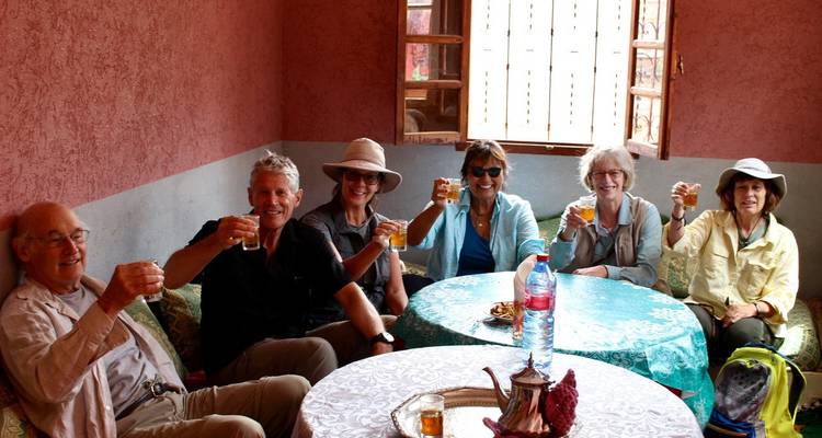 Group of travellers clinking tea glasses inside a local Moroccan home.