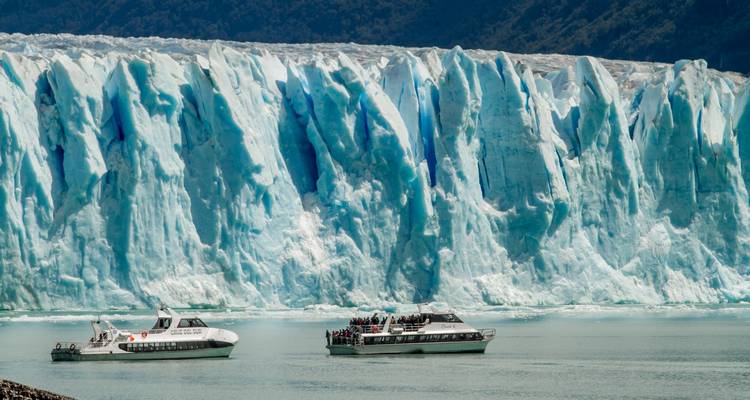 Twee rondvaartboten drijven voor de imposante blauwe ijsmuur van Perito Moreno Gletsjer.