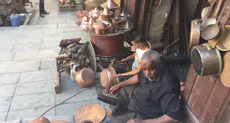 Les artisans du cuivre marocains façonnant des pots à coups de marteau dans un atelier en plein air le long d'une ruelle de la médina.