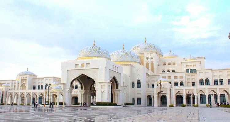 Los majestuosos dómos blancos y arcos del palacio Qasr Al Watan brillan contra un cielo pastel.
