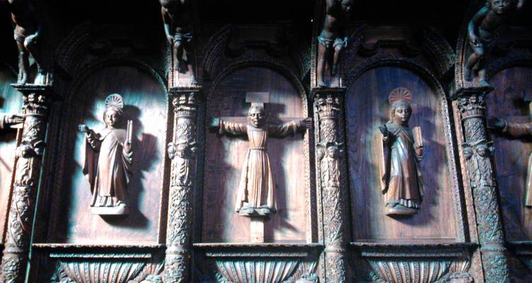 Ingewikkeld gesneden houten heiligen sieren de binnenmuur van een historische Boliviaanse kerk.