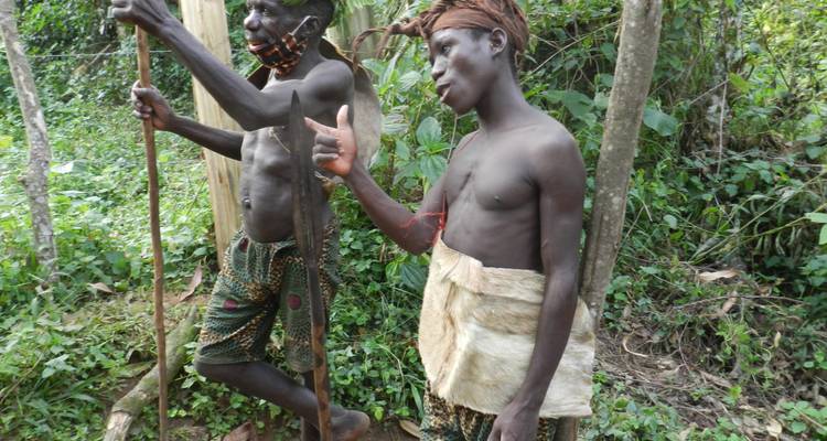 Deux jeunes membres de la tribu avec des lances et de la peinture faciale posant à côté d'une clairière forestière.