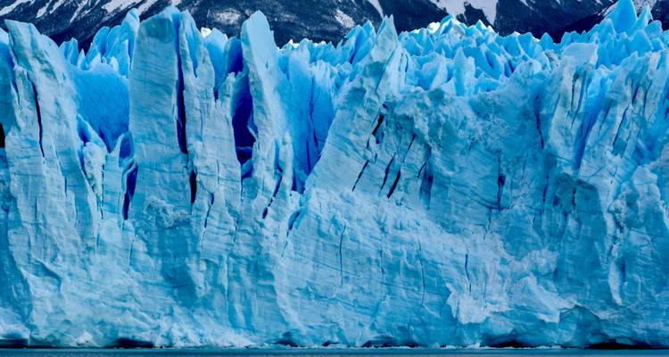 Detalle en primer plano de los imponentes picos de hielo azul de un glaciar patagónico contra cumbres oscuras.