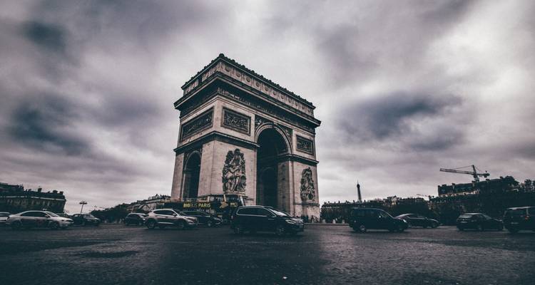 De Arc de Triomphe domineert een sombere lucht terwijl het verkeer rond het beroemde Parijse rondpunt cirkelt.