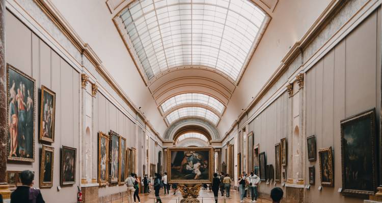 Grote galerij van een kunstmuseum vol meesterwerken onder een gewelfd glazen plafond.