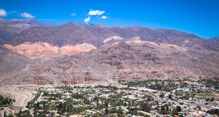 Vue panoramique d'une chaîne de montagnes multicolores dominant une petite ville désertique.