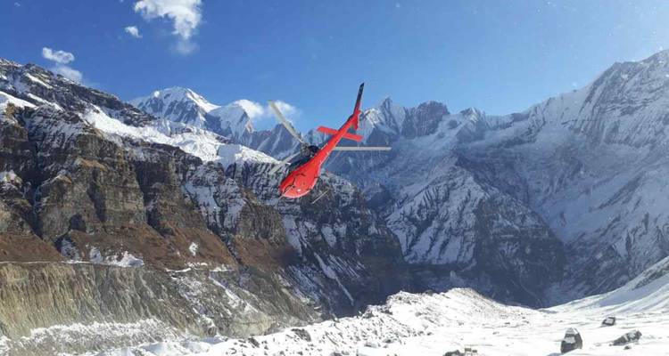 A red helicopter soars above snow-covered Himalayan peaks and deep glacial valleys.