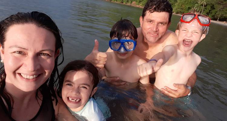Familia feliz salpicando y posando con máscaras de buceo en aguas tropicales poco profundas