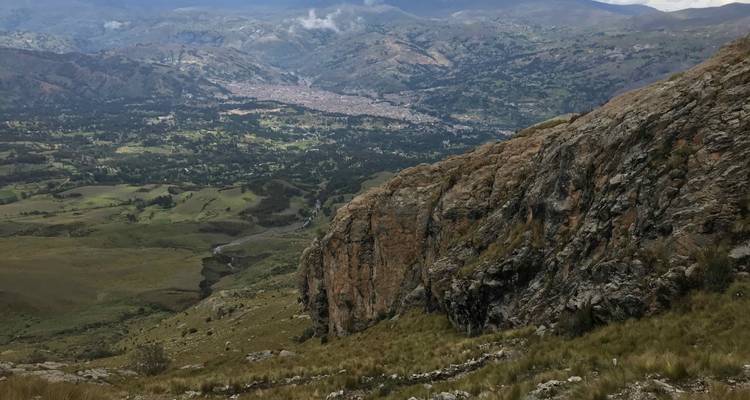 Felsige Steilküste mit Blick auf ein breites Tal und die entfernte Stadt Cusco