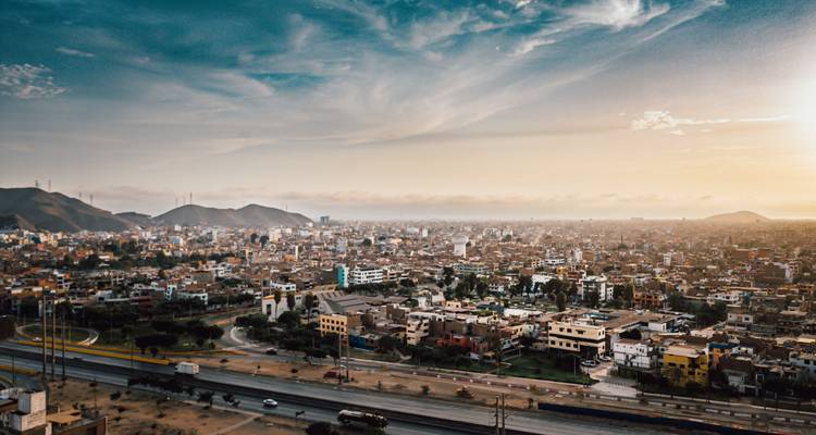 Breite Sonnenuntergangspanorama über die sich ausbreitende Stadtlandschaft von Lima mit entfernten Hügeln