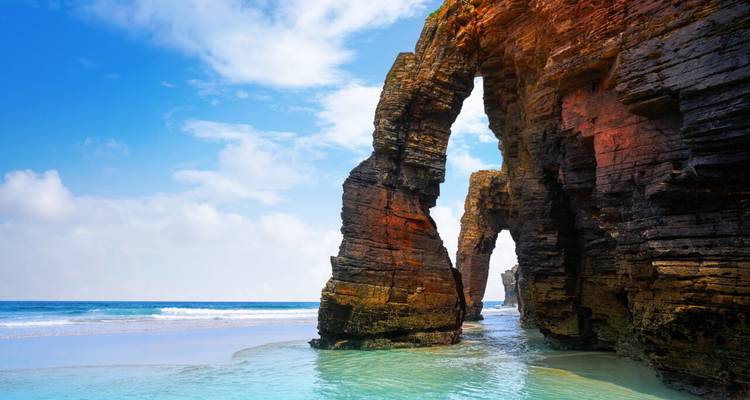 Cathedral Beach's dramatic natural rock arches rising from turquoise Atlantic waters on a sunny day.