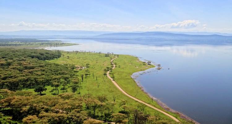 Vue aérienne d'un vaste lac aux rives sinueuses et de plaines verdoyantes luxuriantes sous un ciel bleu